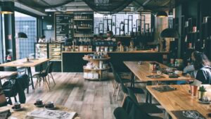 a trendt coffee shop with rectangular tables in the foreground and the counter behind