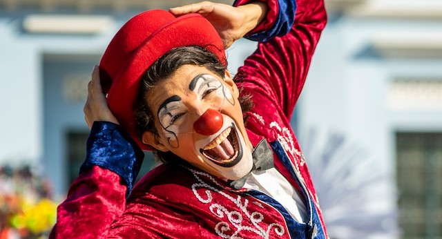 a happy clown in a vivid red outfit laughs at the camera