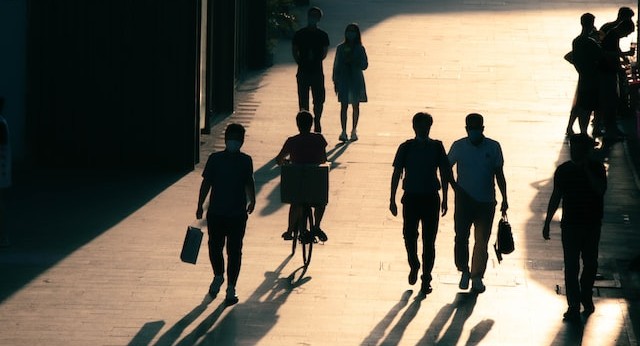 a silhouette of 4 three pedestrians with a cyclist having just past between them, cycling away from the camera