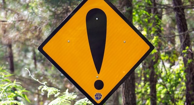 A road warning sign consisting of a big exclamation mark against a yellow diamond