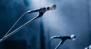 two microphones on a spotlit stage, with dry ice