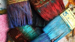 a montage of paintbrushes, their heads dipped in differing colours of paint