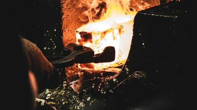 a red hot metal ingot being held in a furnace by metal tongs
