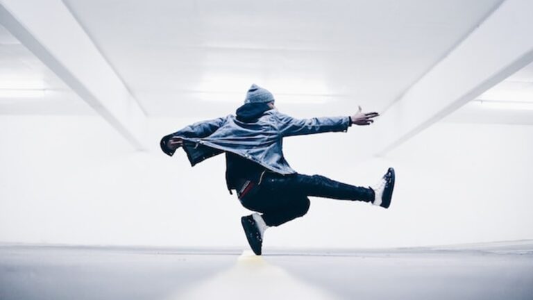 a silhouette of a dancer, mid air, kicking one leg out and with arms outstretched