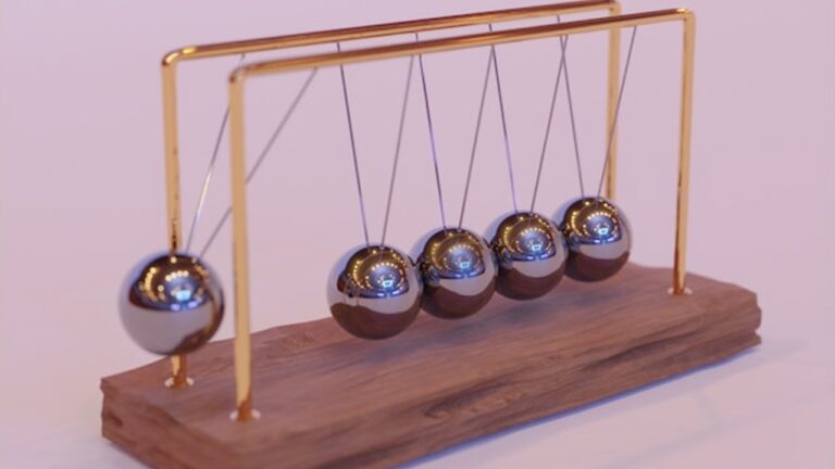 a newton's cradle with the left most of five silver balls about to descend towards the pack